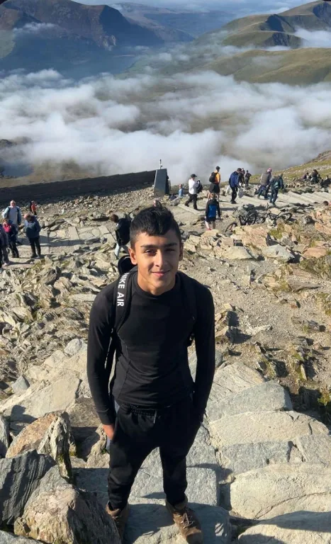 Oliver Rorzkowski hiking on a rocky mountain trail above the cloud line